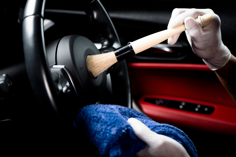 Detailer brushing a car steering wheel during an interior detail in Newcastle