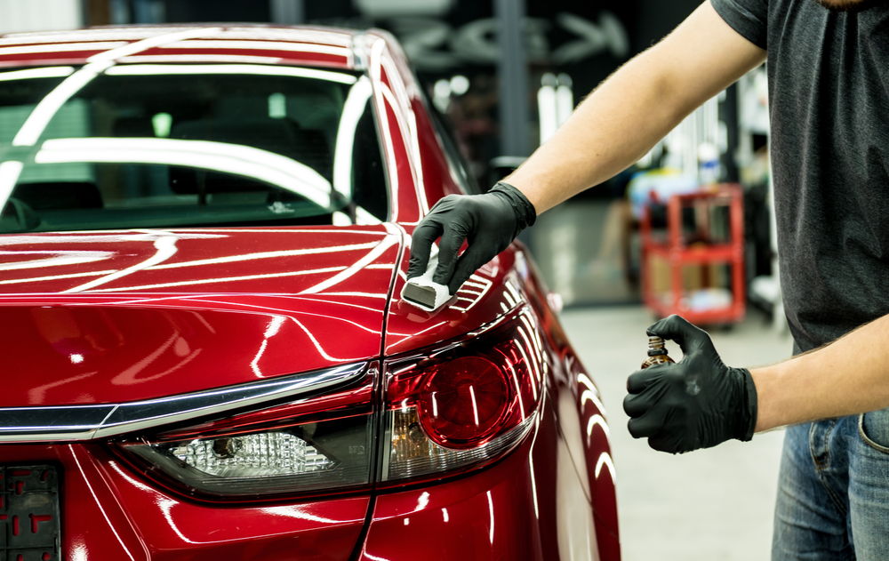 Detailer applying ceramic coating to the rear panel of a red car at the Broadmeadow studio