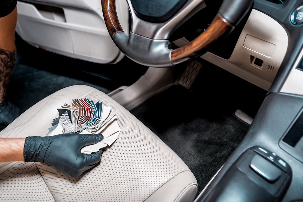 Detailer cleaning a cream leather car seat during an interior detail in Newcastle