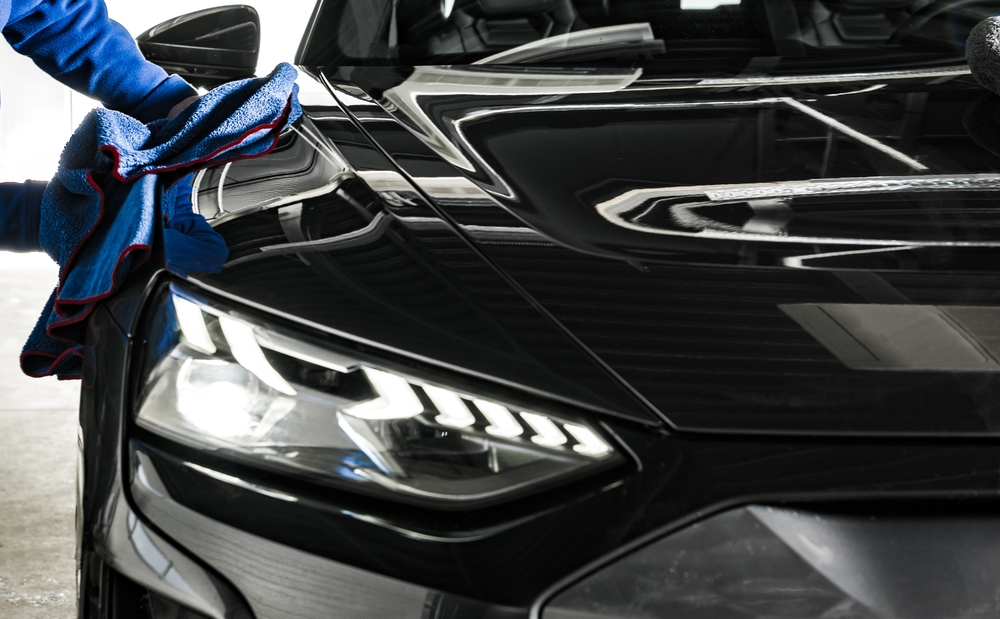 Detailer buffing the bonnet of a black car with a microfibre cloth at the Broadmeadow detailing studio