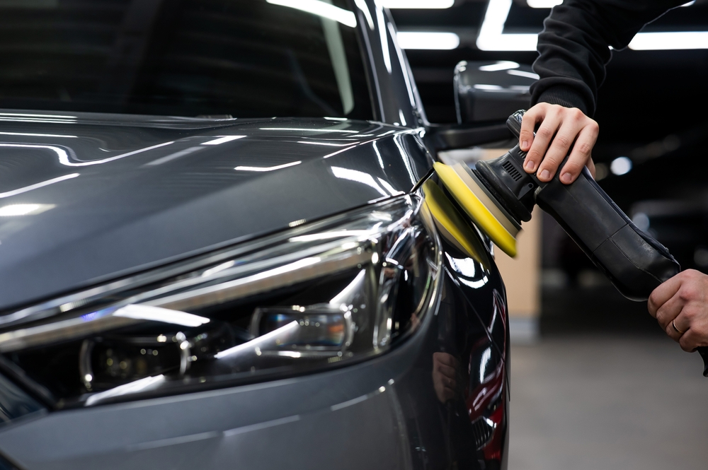 Detailer machine polishing the front guard of a grey car during paint correction